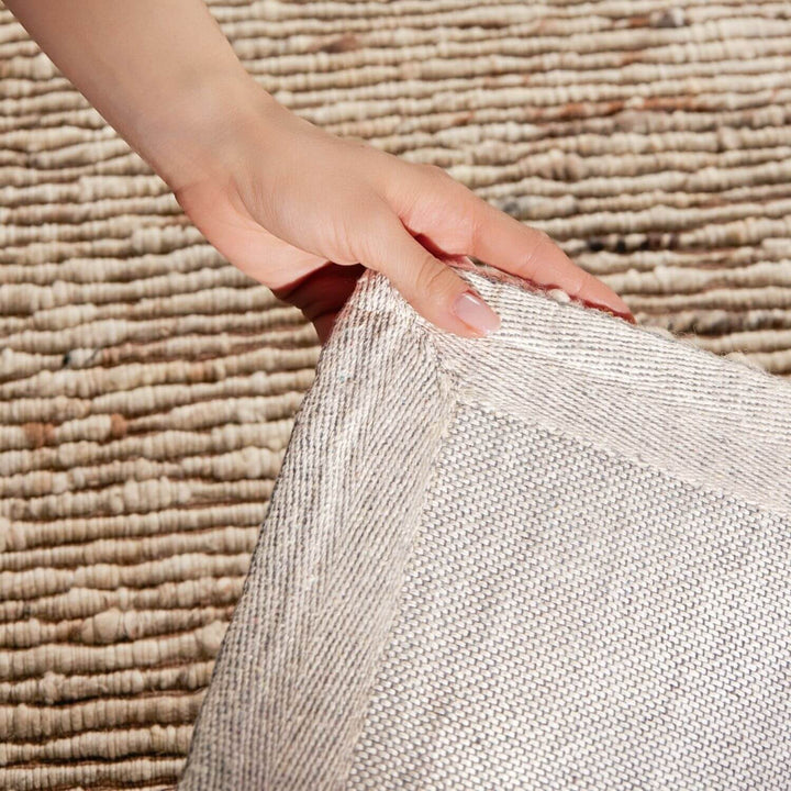 Hand holding a textured fabric against a woven background