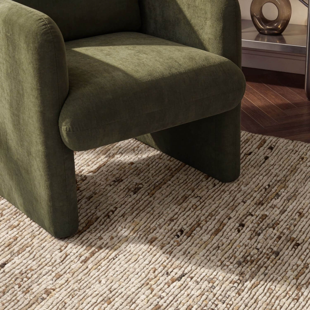 Green armchair on a textured rug with a blurred background