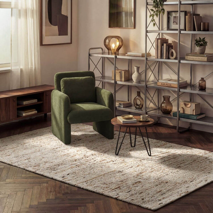 Green armchair in a living room with a bookshelf and table.