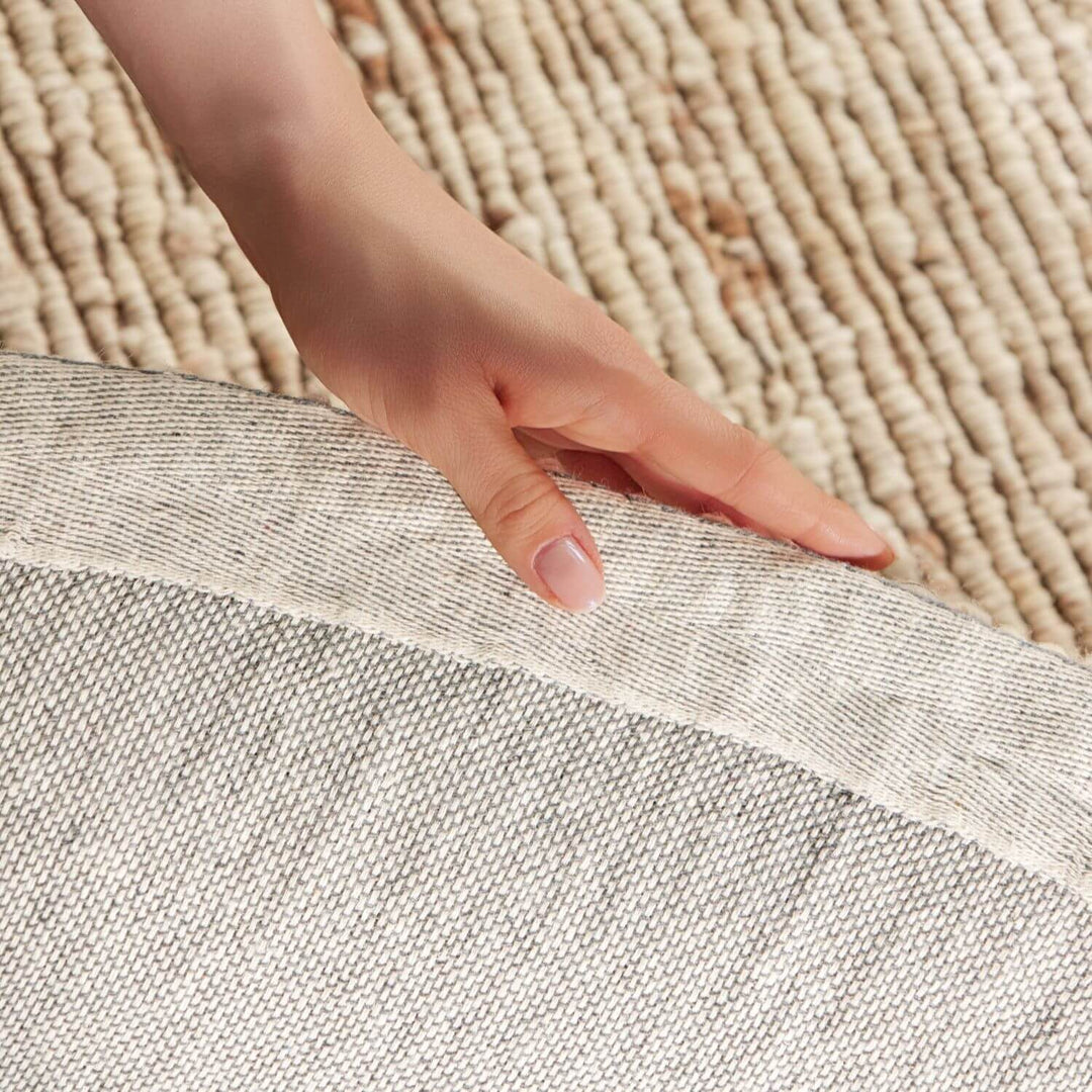 Hand touching the edge of two different textured rugs.