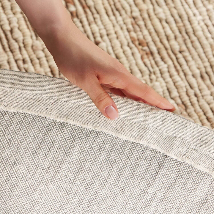 Hand touching the edge of two different textured rugs.
