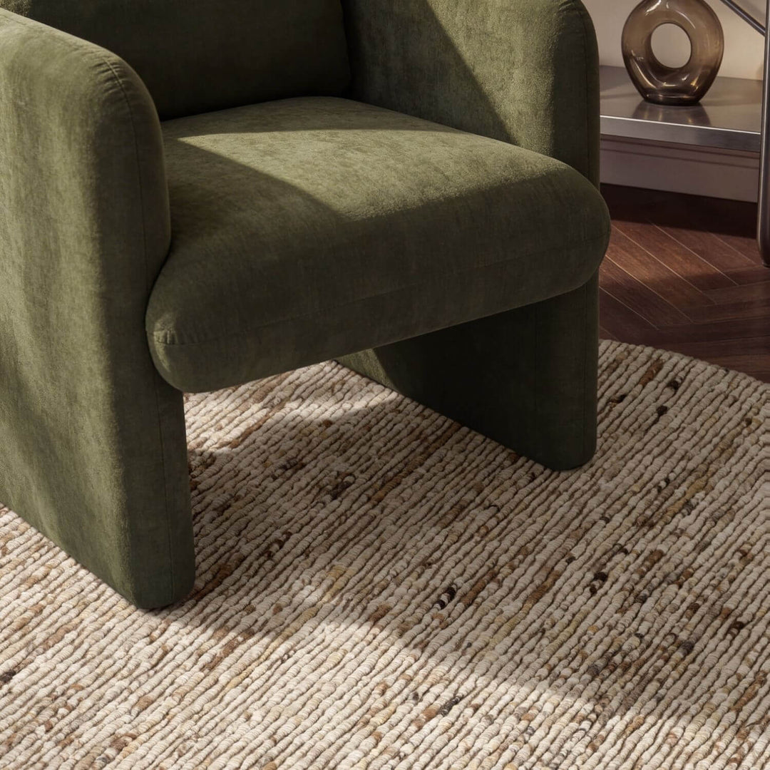 Green armchair on a textured rug with a blurred background