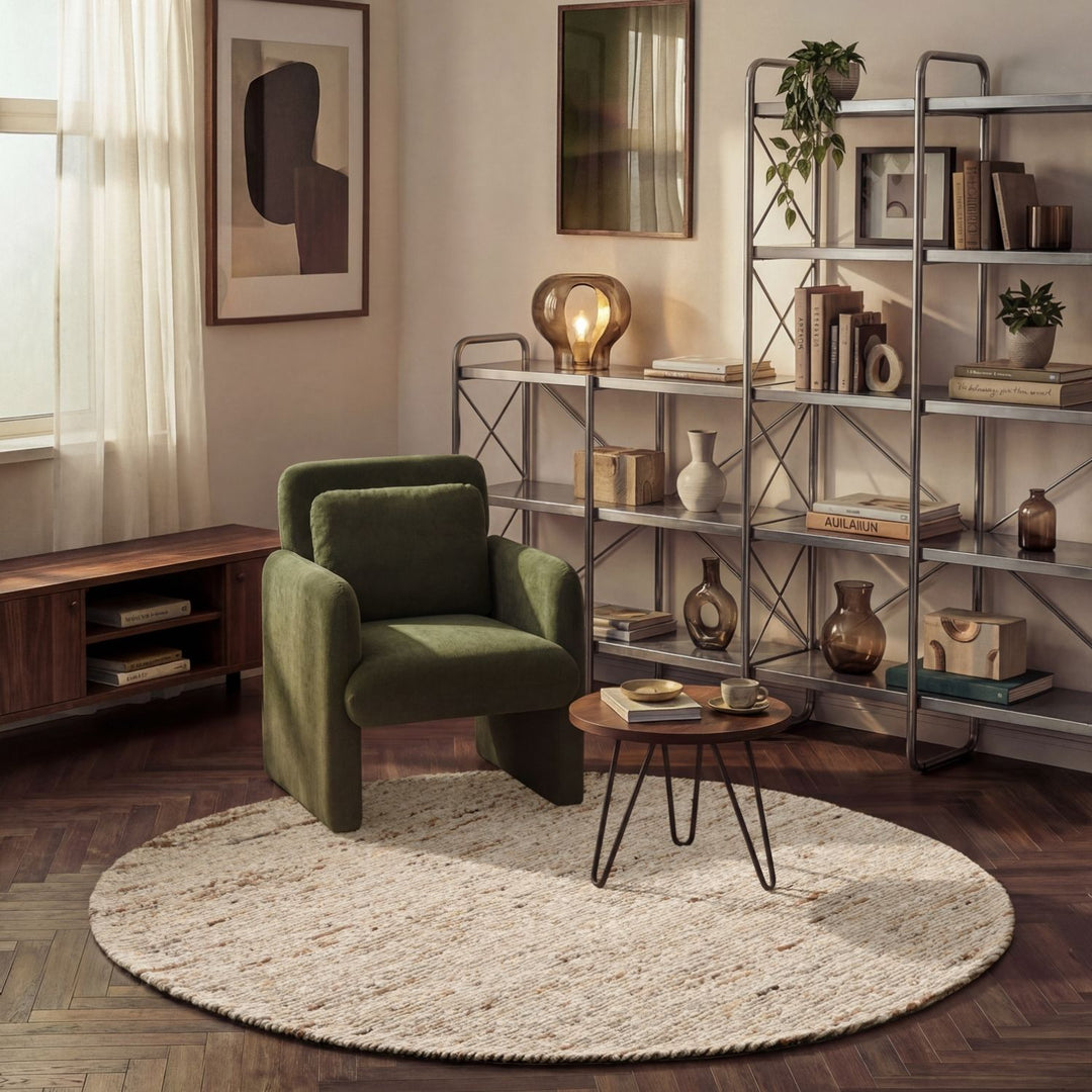 Modern living room with a green armchair, round rug, and bookshelf.