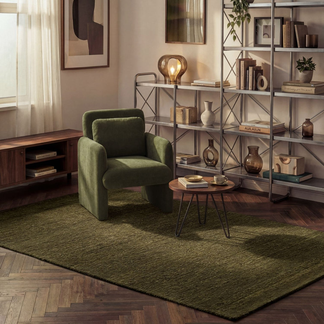 Green armchair in a living room with a bookshelf and decorative items.