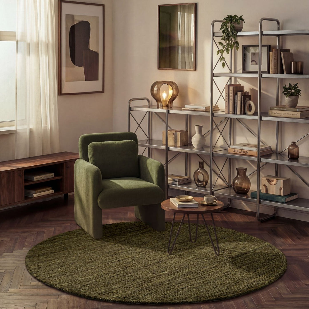 Living room with green armchair, round rug, and bookshelf.