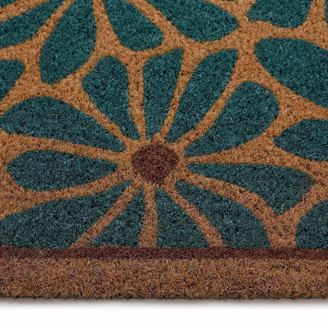 Close-up of a doormat with a floral pattern in teal and brown.