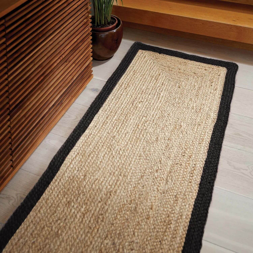 Beige jute rug with black border on a wooden floor