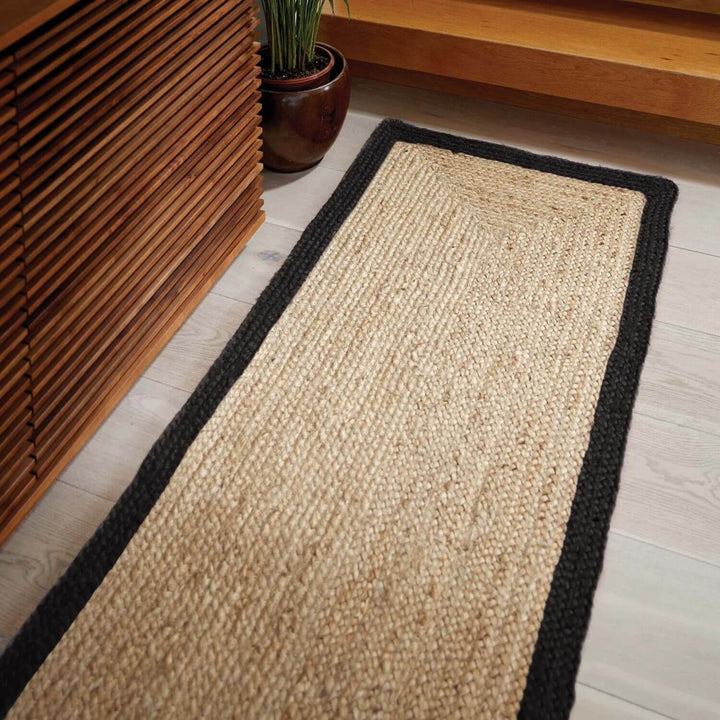 Beige jute rug with black border on a wooden floor