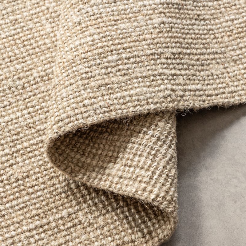 Close-up of a textured beige fabric with a soft shadow on a neutral background