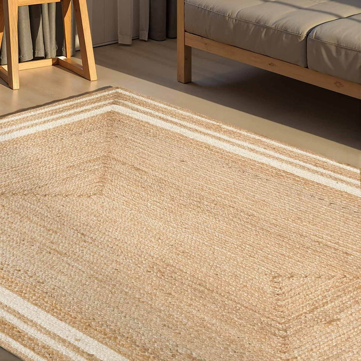 Close-up of a woven beige rug with a wooden chair and sofa in the background.