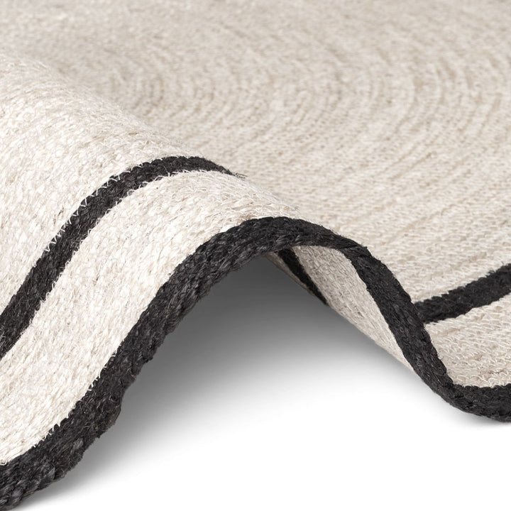 Close-up of a textured rug with black stripes on a white background