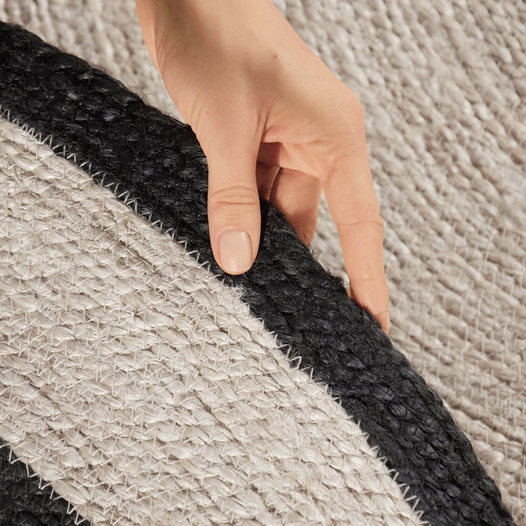 Hand touching a textured black and gray rug