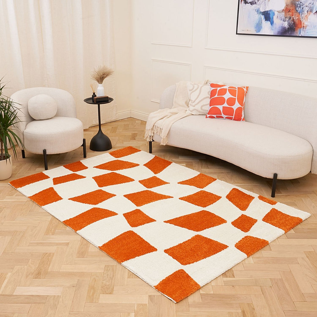Living room with a geometric orange and white rug, white sofa, and armchair.