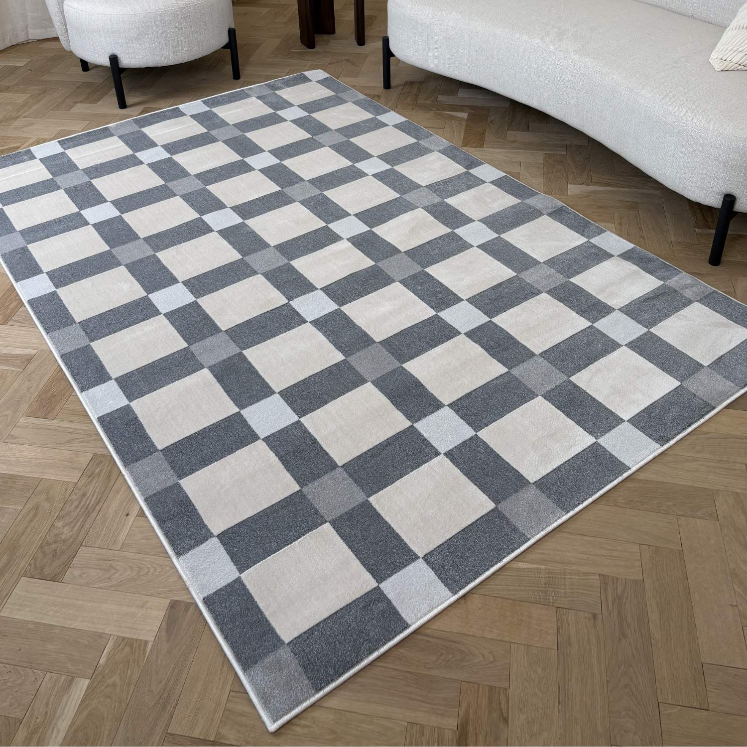 Checkered area rug on a wooden floor with a sofa and chair in the background