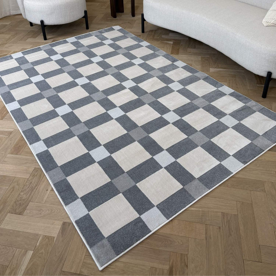 Checkered area rug on a wooden floor with a sofa and chair in the background