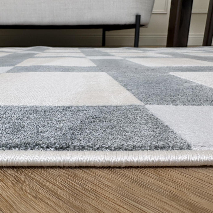 Checkered area rug with gray and white squares on a wooden floor.