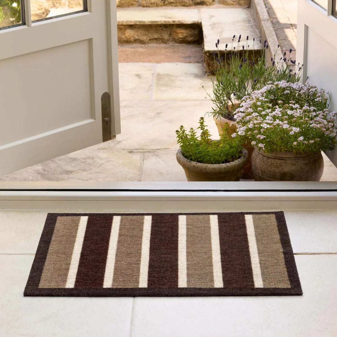 Striped doormat in front of a glass door with plants on a patio