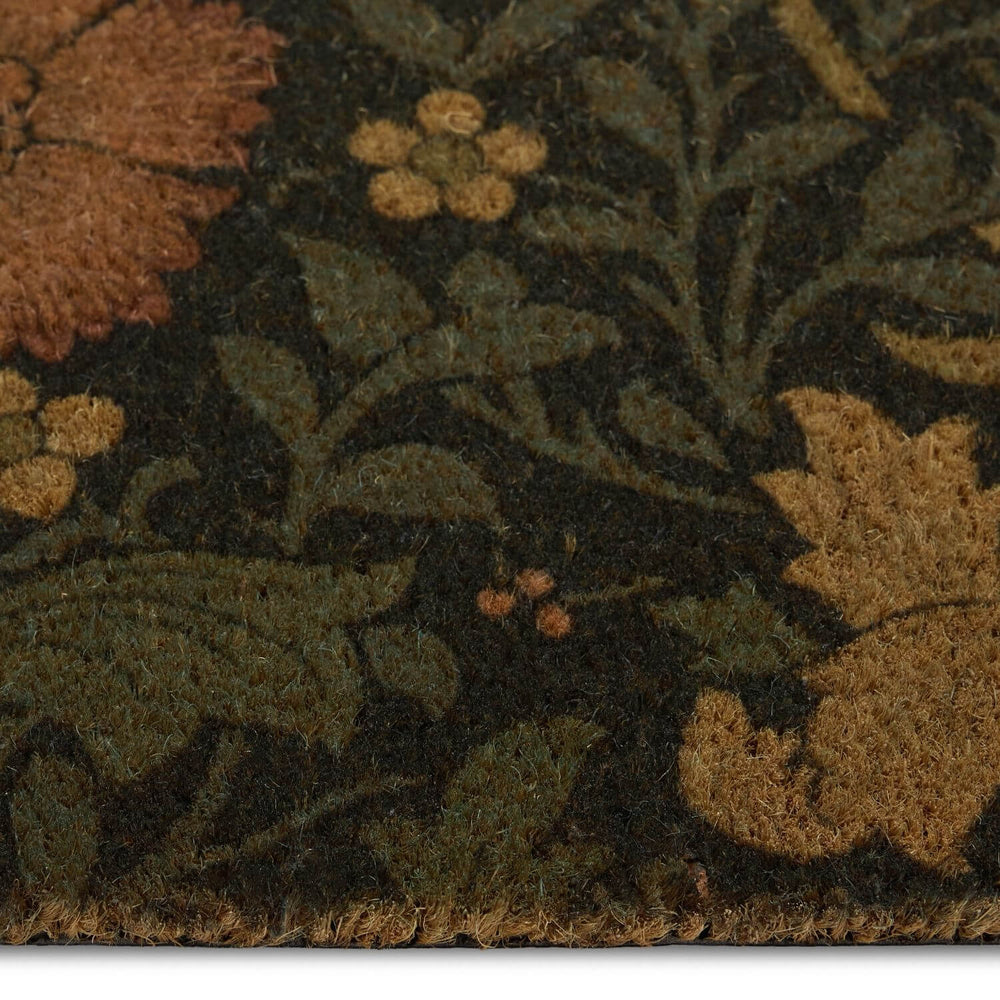 Close-up of a floral patterned rug with green, brown, and orange colors.