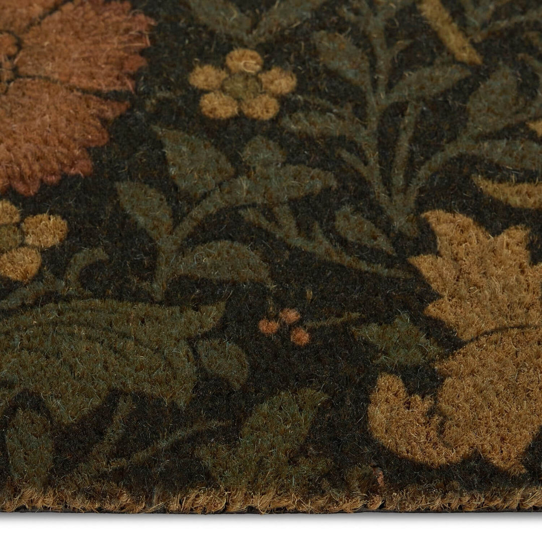 Close-up of a floral patterned rug with green, brown, and orange colors.