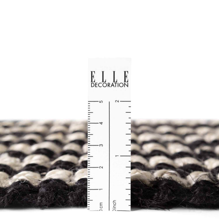 Textured black and white rug with a ruler for scale on a white background, featuring the 'ELLE Decoration' brand.