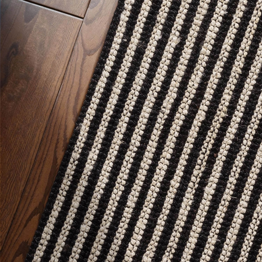 Close-up of a black and white striped rug on a wooden floor.
