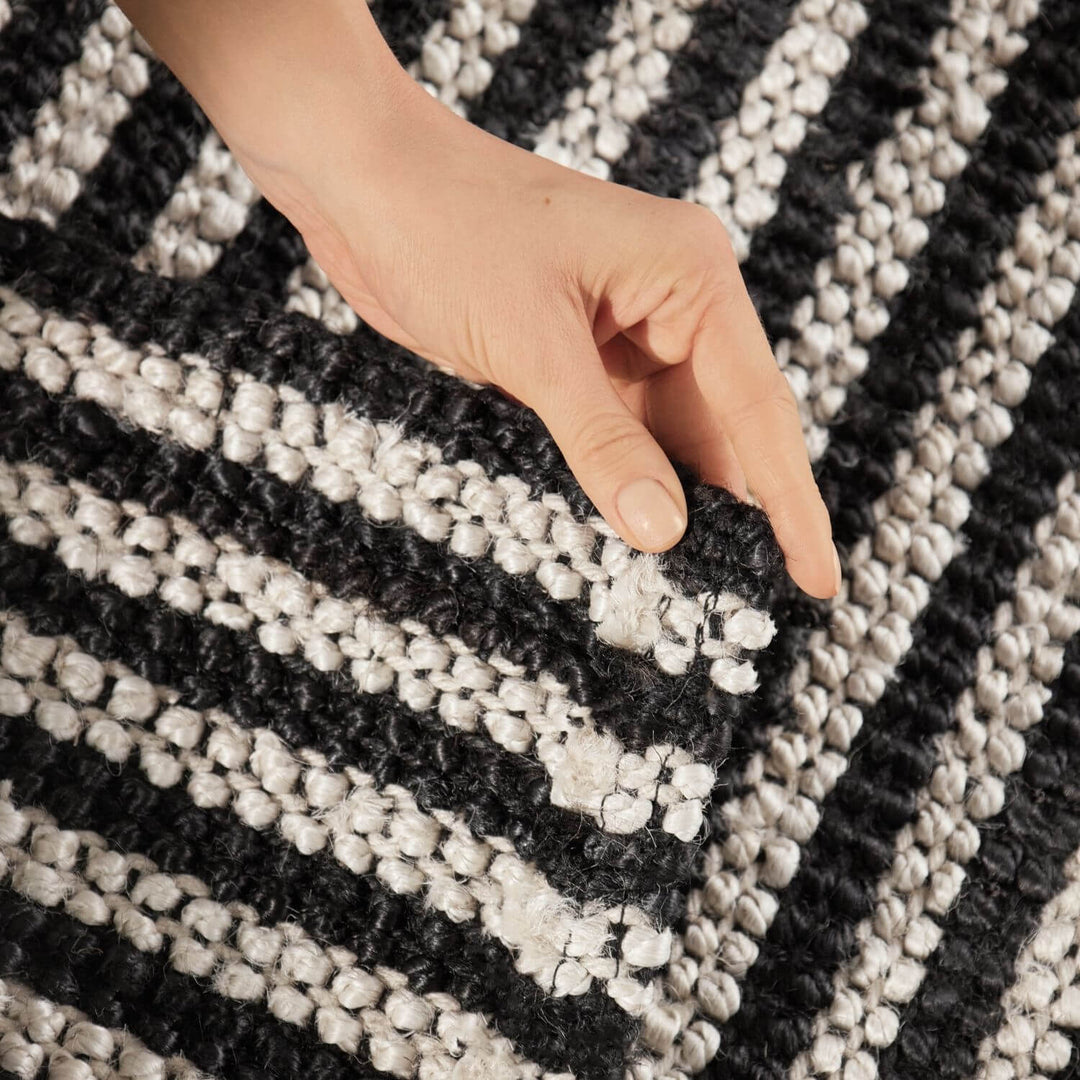 Hand touching a textured black and white rug