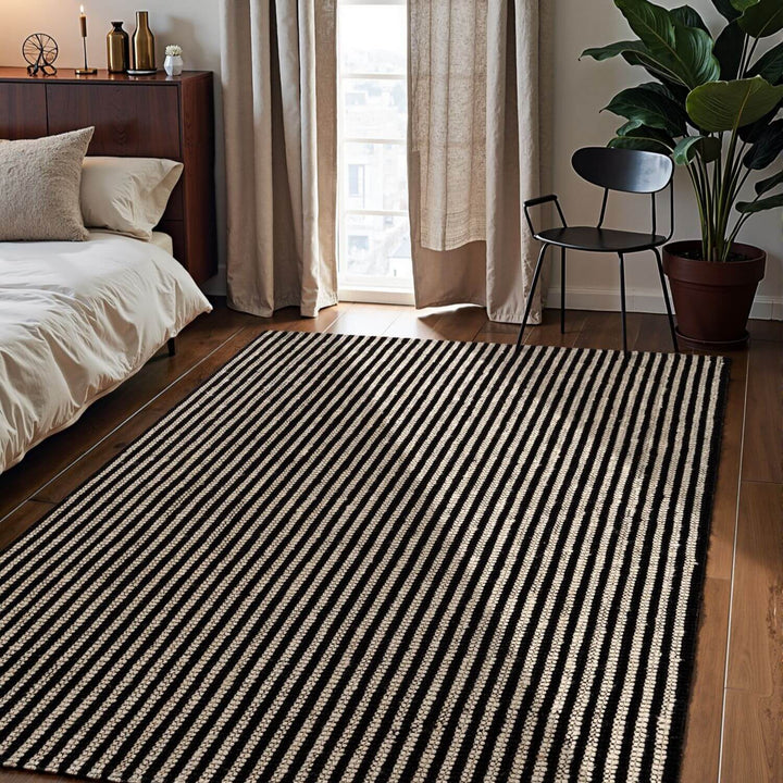 Striped rug in a bedroom with a bed, chair, and plant.