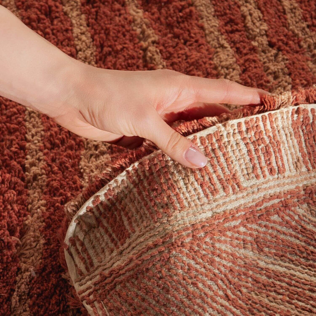Hand touching a textured brown and beige fabric