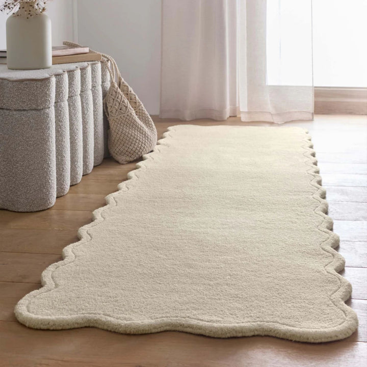 Beige rug on a wooden floor with a white curtain in the background