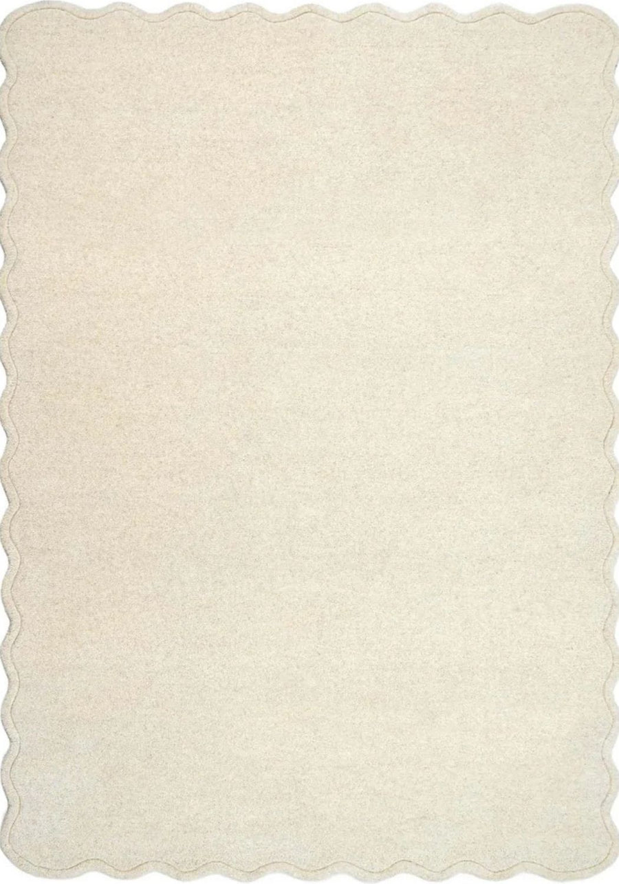 Beige rug with scalloped edge on a white background