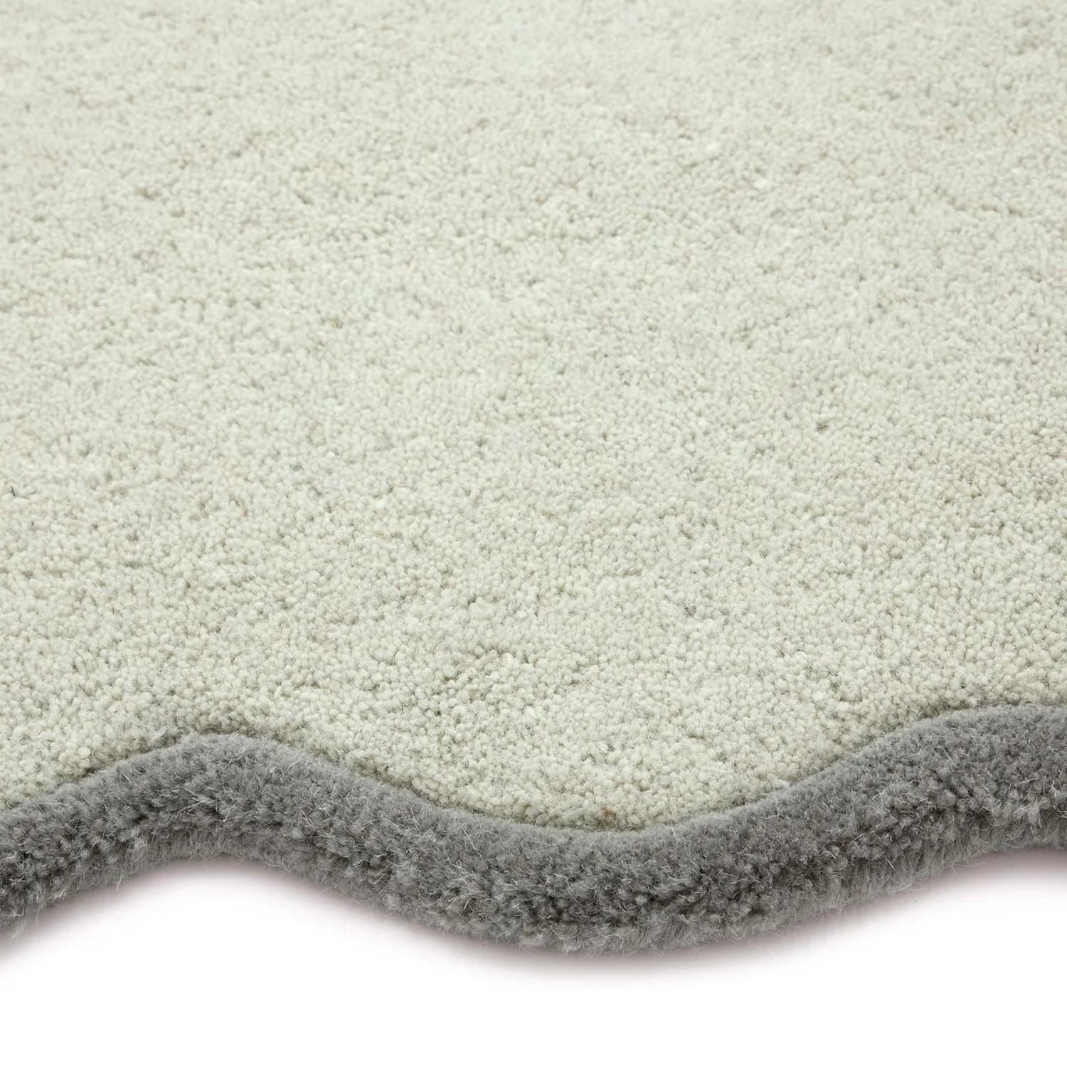 Close-up of a textured gray rug corner on a white background