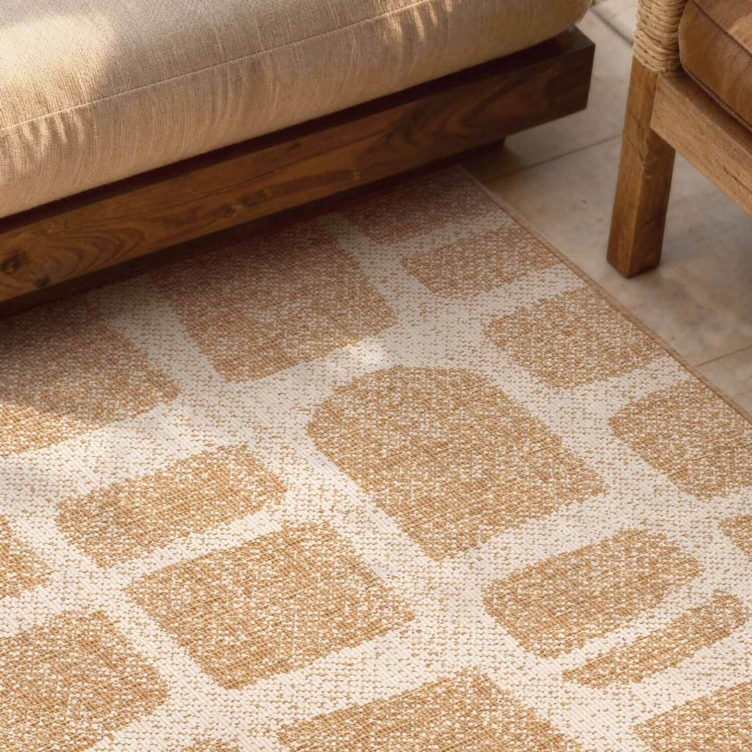 Patterned beige rug on a wooden floor with a sofa and chair in the background