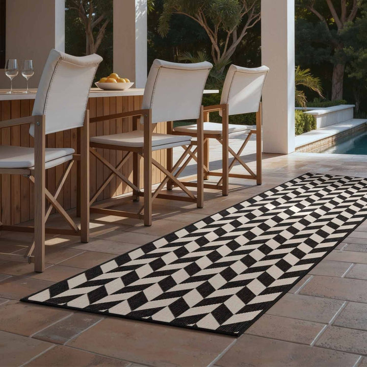 Outdoor dining area with wooden chairs and a black and white patterned rug.