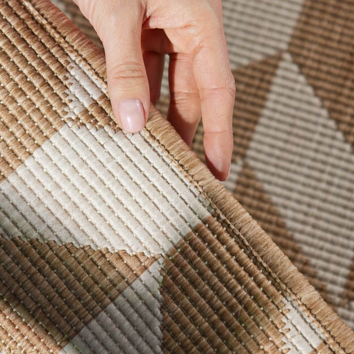 Close-up of a hand touching a textured brown and beige fabric