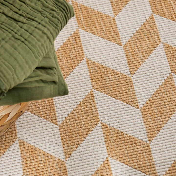Geometric patterned rug with a green pillow on top