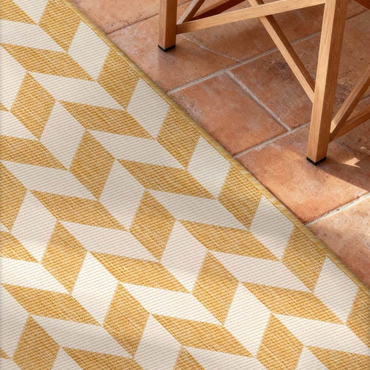 Yellow and white geometric patterned rug on terracotta tiles