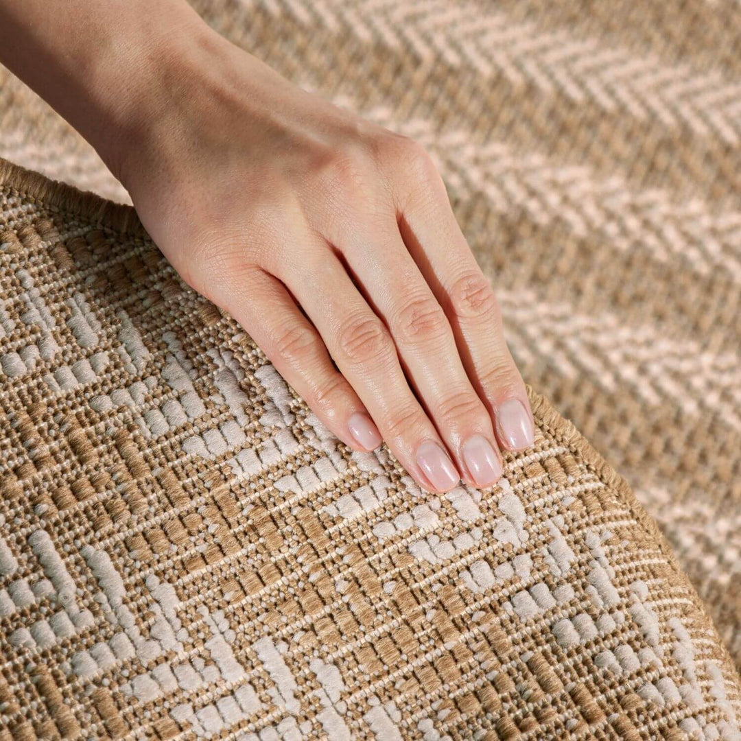Hand with light pink nail polish resting on a textured woven surface