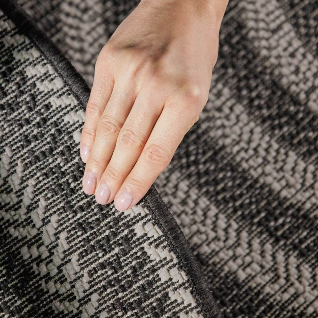 Hand touching a textured gray and black fabric surface