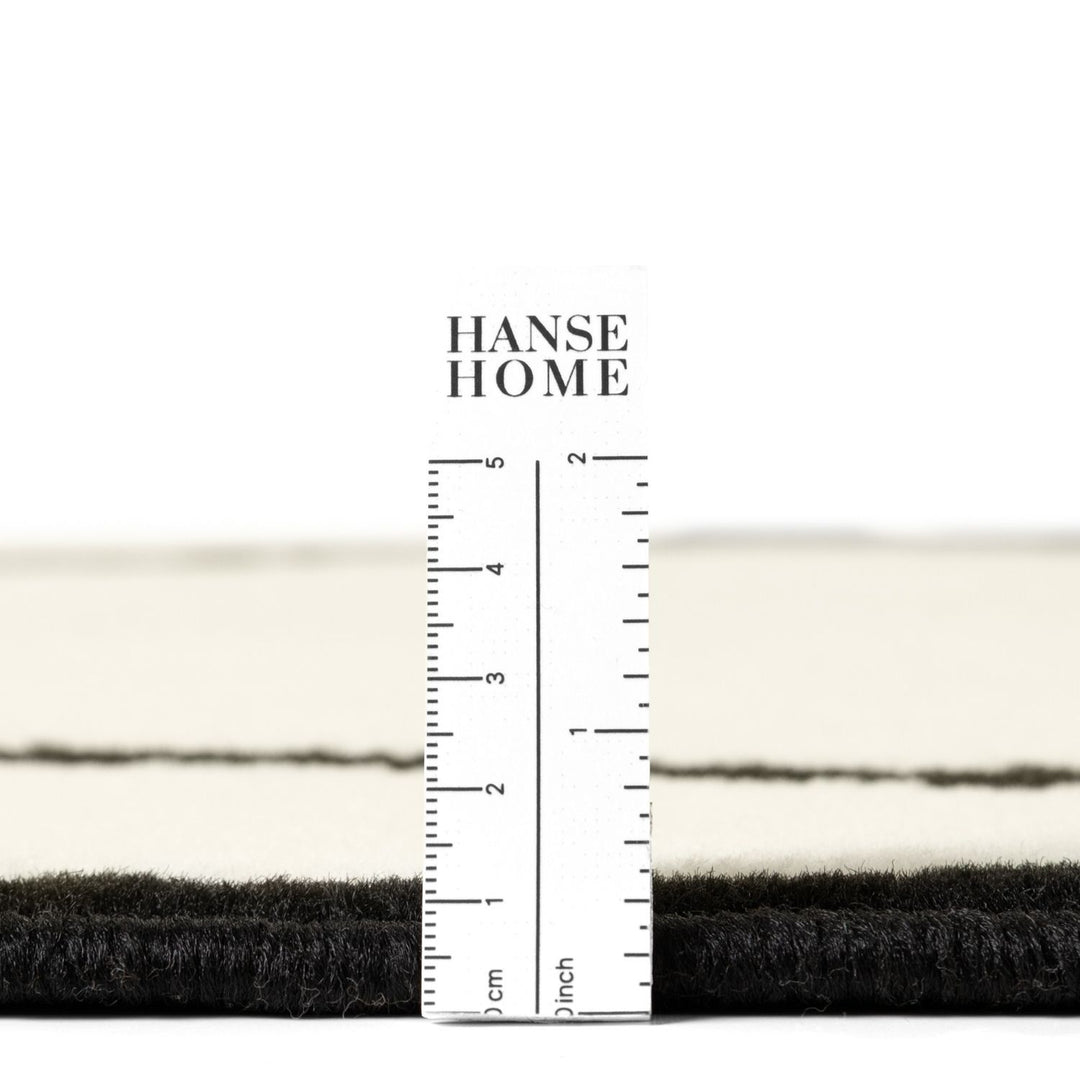 Close-up of black and white fabric with a ruler for measurement, branded 'HANSE HOME'.