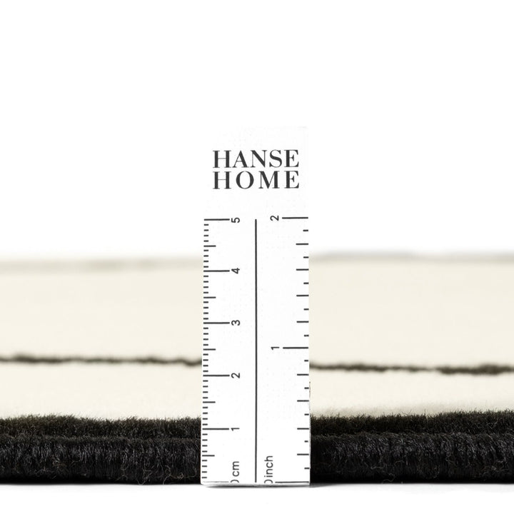 Close-up of black and white fabric with a ruler for measurement, branded 'HANSE HOME'.