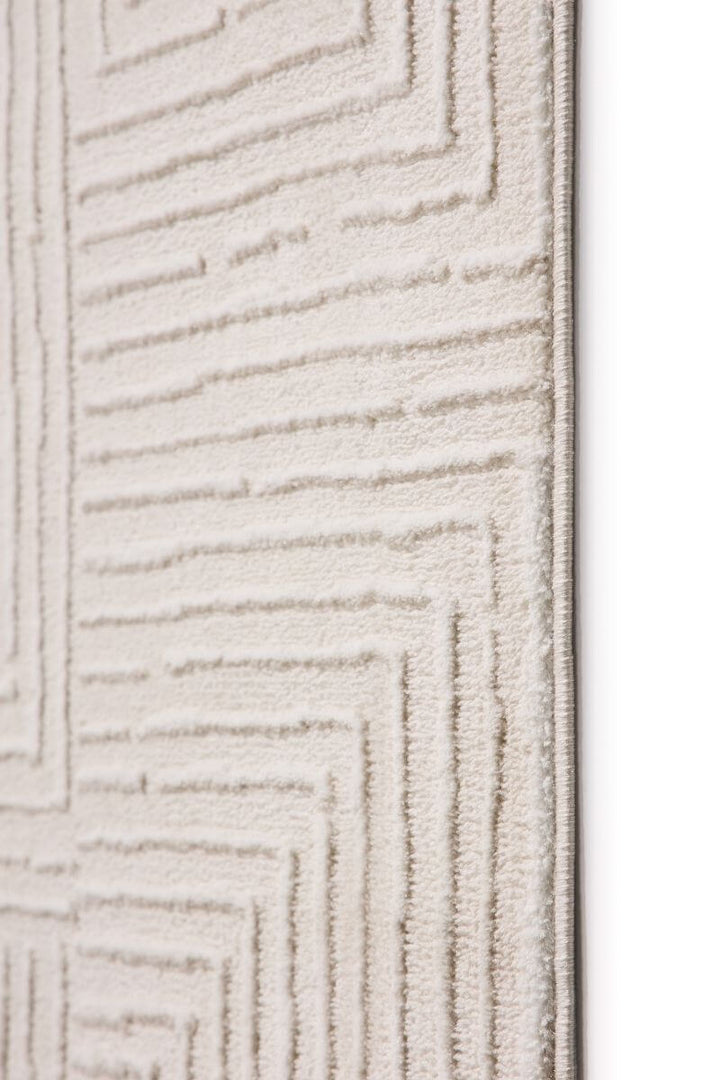 Close-up of an abstract geometric rug in cream shades, featuring clean lines and a textured surface.
