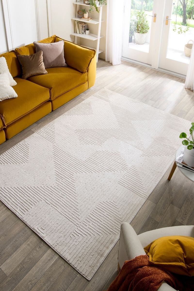 Abstract geometric rug in cream tones, enhancing a modern living room with yellow couch and natural light.