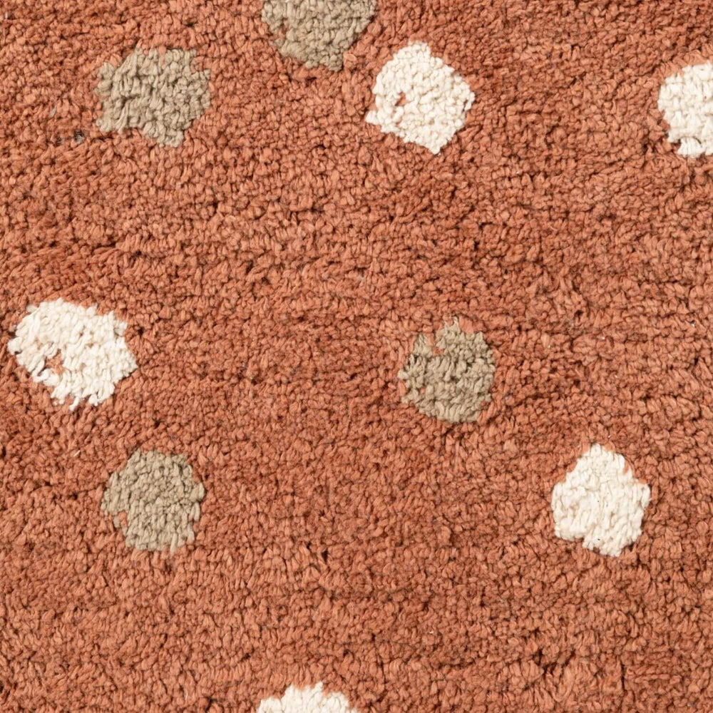 Close-up of a textured brown carpet with white and beige spots