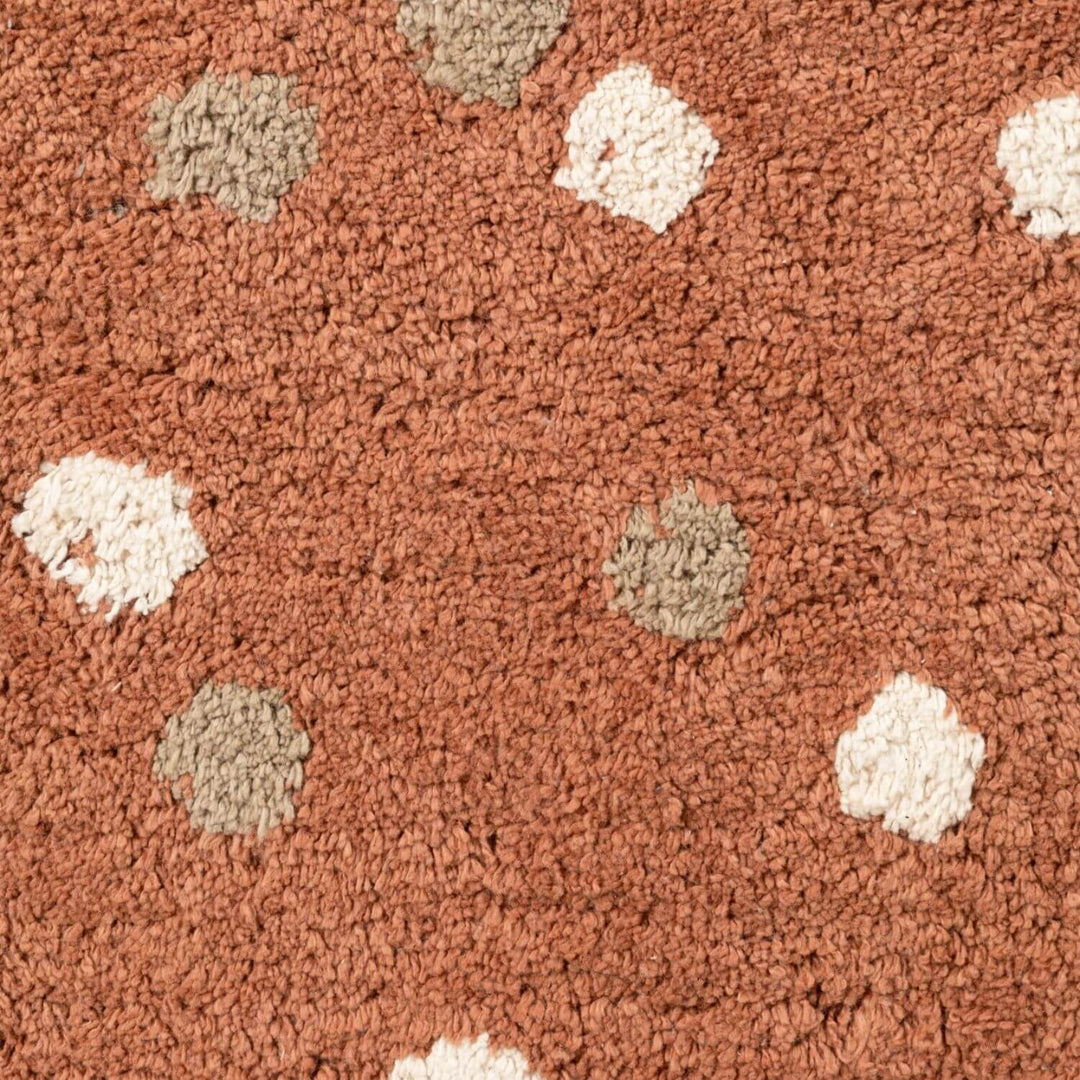 Close-up of a textured brown carpet with white and beige spots