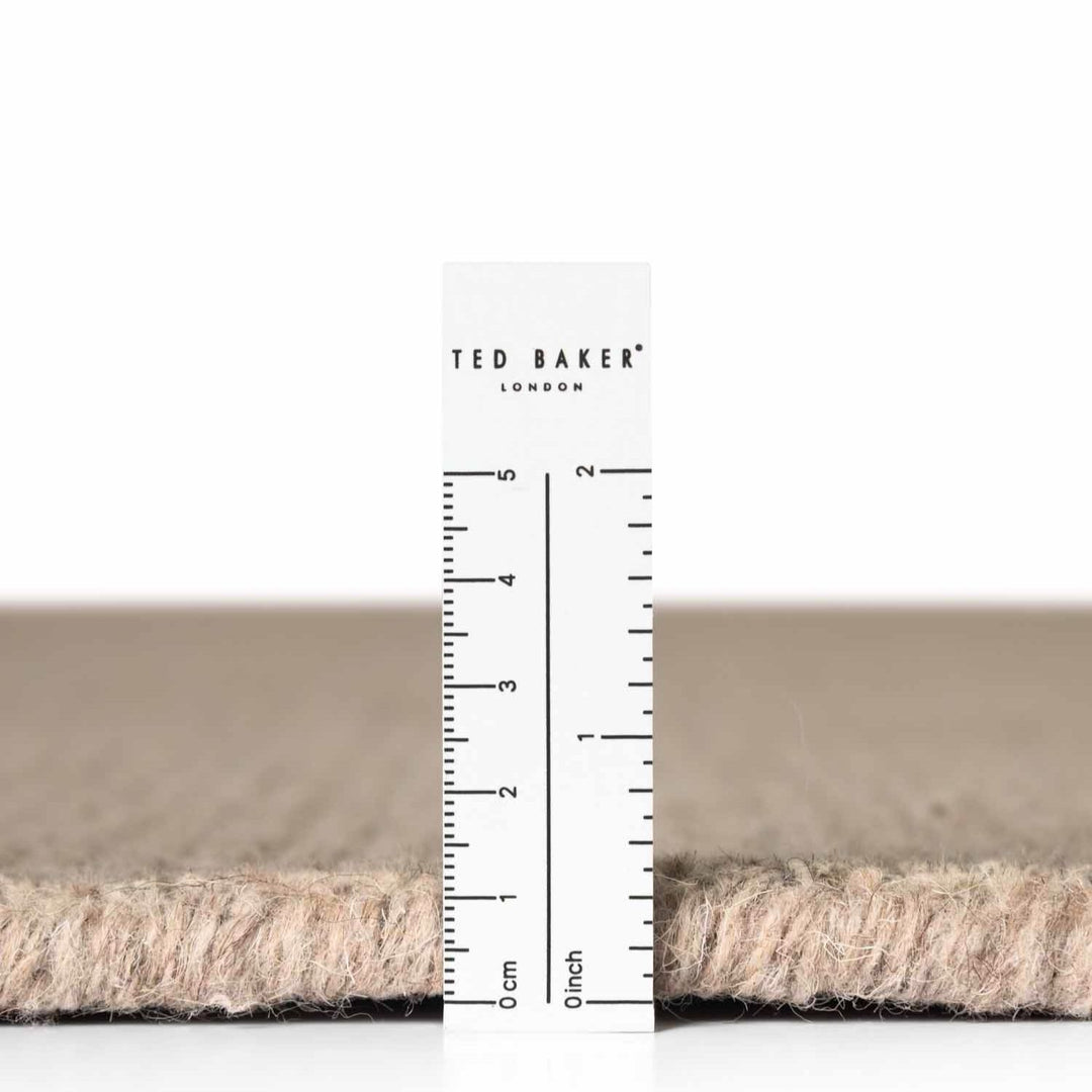 Close-up of a carpet sample with a ruler and 'Ted Baker London' branding.