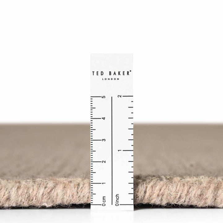 Close-up of a carpet sample with a ruler and 'Ted Baker London' branding.