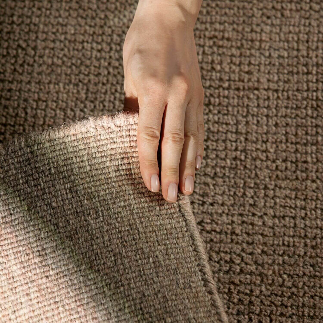 Hand touching a textured brown fabric surface