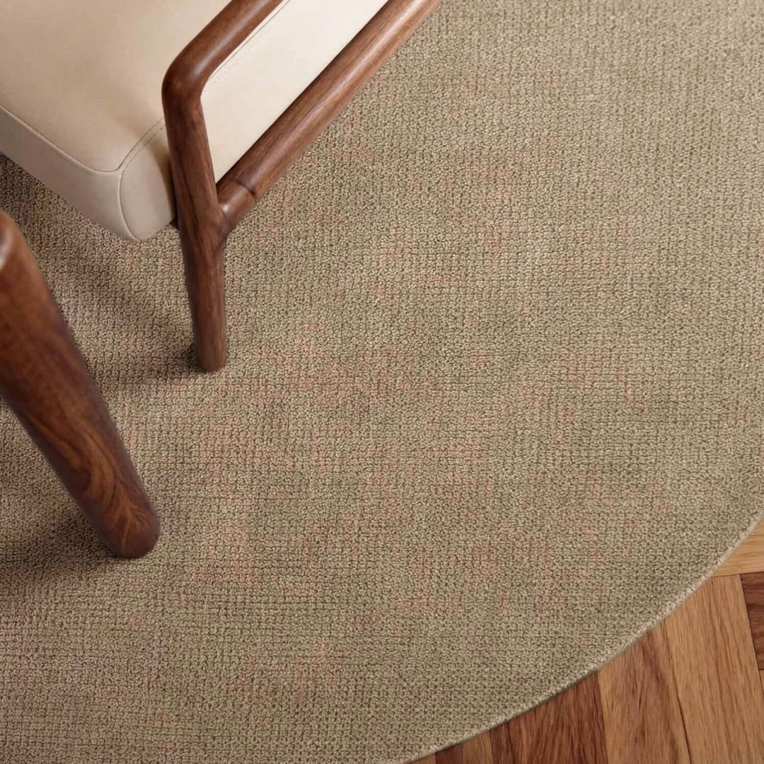Close-up of a textured beige carpet with wooden furniture legs.