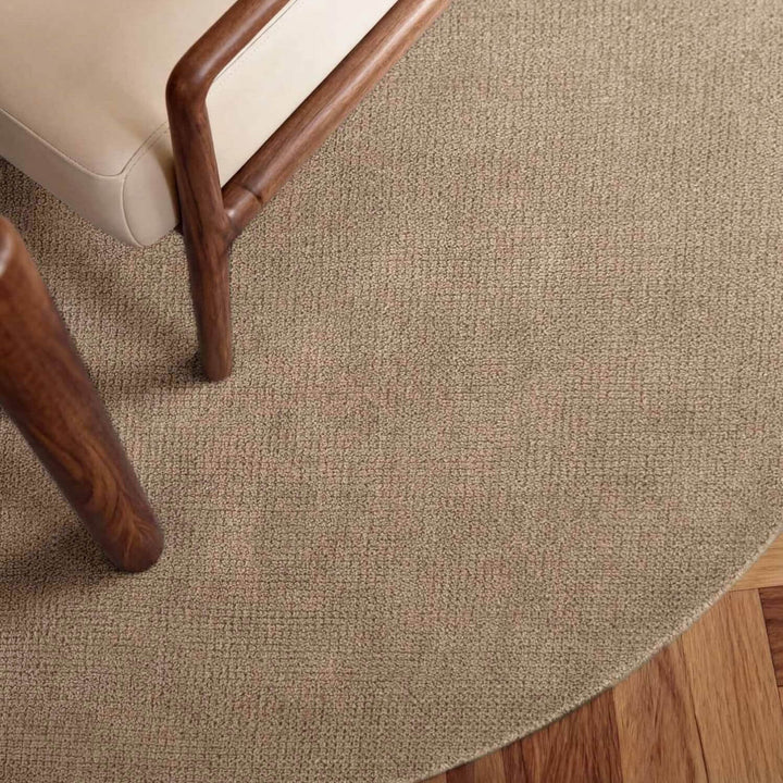 Close-up of a textured beige carpet with wooden furniture legs.