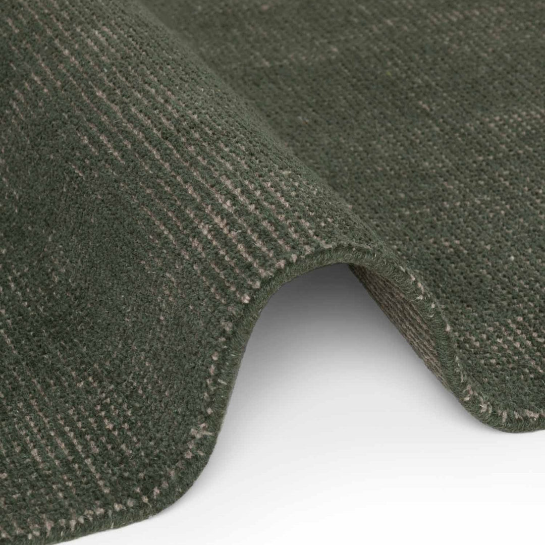 Close-up of a green textured rug corner on a white background